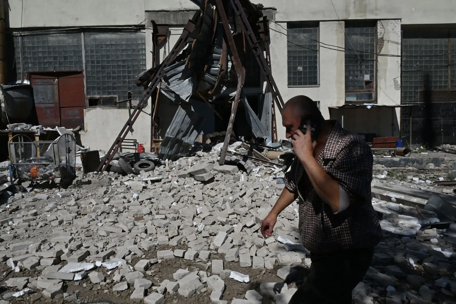 Un hombre habla por teléfono mientras camina entre los escombros cerca de Press House, un complejo de una imprenta, oficinas editoriales y tiendas en Kharkiv dañado por el ataque con misiles.
Foto: AFP