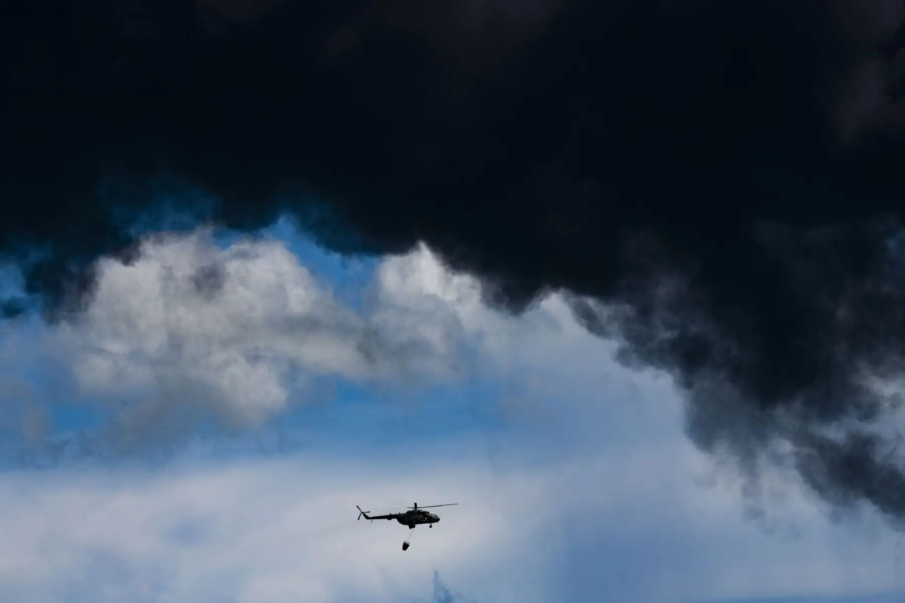 Un helicóptero de extinción de incendios se ve cerca del tanque de petróleo en llamas en Matanzas, Cuba. El incendio provocado por un rayo el viernes en un depósito de combustible en Matanzas, en el oeste de Cuba, se extendió a un segundo tanque en la madrugada.
Foto: AFP
