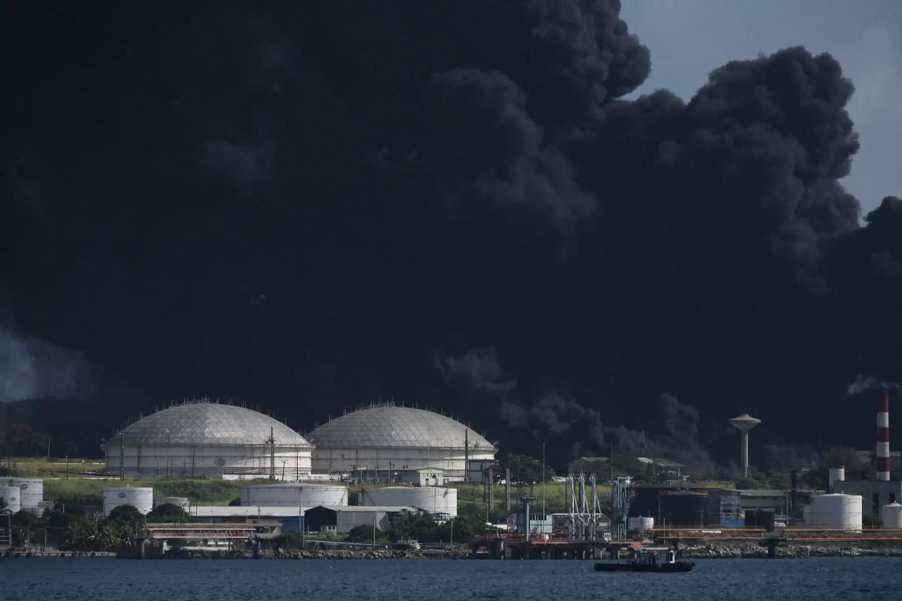 Humo negro de un tanque de petróleo en llamas se ve en Matanzas, Cuba. El incendio provocado por un rayo el viernes en un depósito de combustible en Matanzas, en el oeste de Cuba, se extendió a un segundo tanque en la madrugada de este sábado y causó 49 heridos.
Foto: AFP
