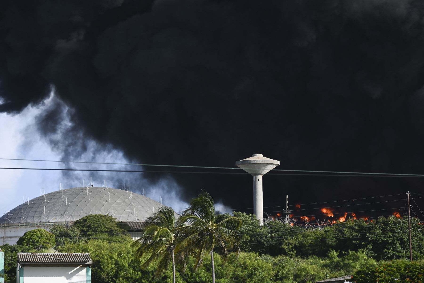 Humo negro de un tanque de petróleo en llamas se ve en Matanzas, Cuba. El incendio provocado por un rayo el viernes en un depósito de combustible en Matanzas, en el oeste de Cuba, se afianzó a un segundo tanque en la madrugada de este sábado y causando 49 heridos.
Foto: AFP