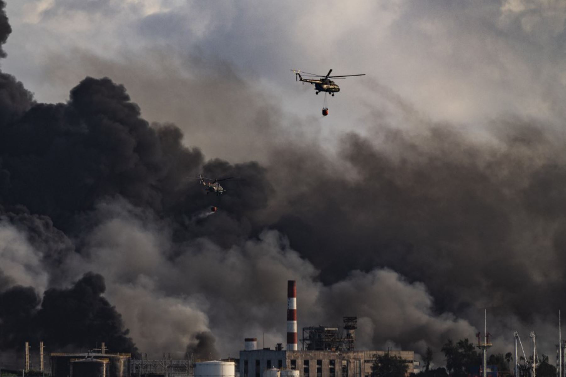 Un helicóptero de bomberos arroja agua sobre un incendio masivo en un depósito de combustible provocado por un rayo en Matanzas, Cuba. Foto: AFP