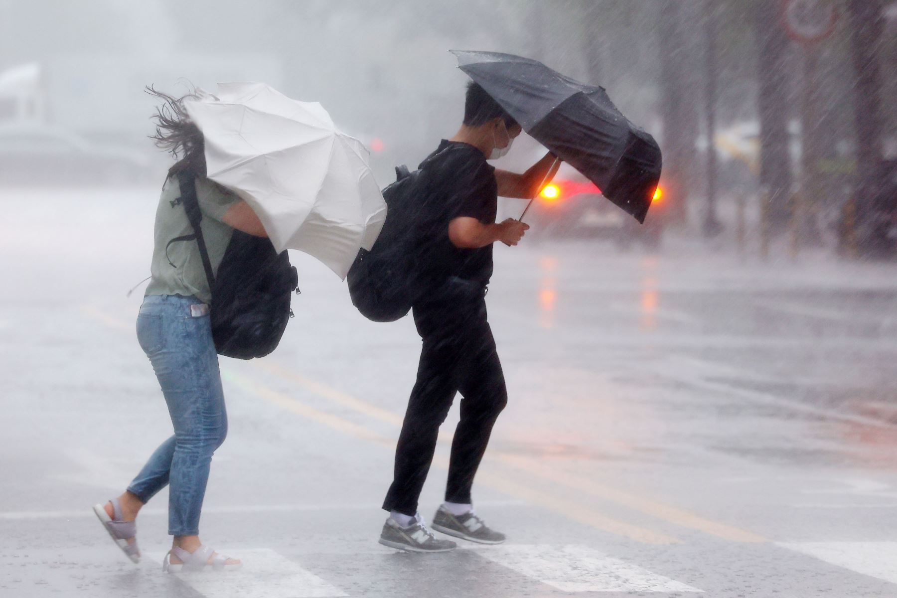 Dos personas intentan protegerse de la fuerte lluvia mientras cruzan un paso de peatones en Seúl, Corea del Sur.
Foto: EFE