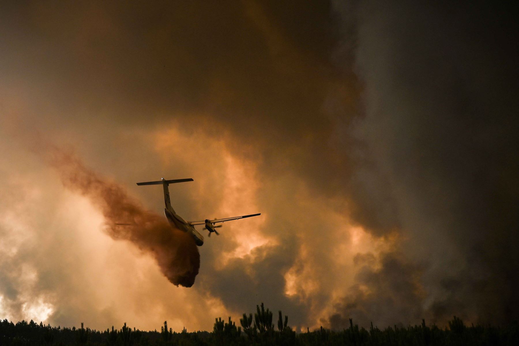 Un avión de extinción de incendios rocía retardante de fuego sobre los árboles durante un incendio forestal cerca de Belin-Beliet en Gironde, suroeste de Francia. Foto: AFP