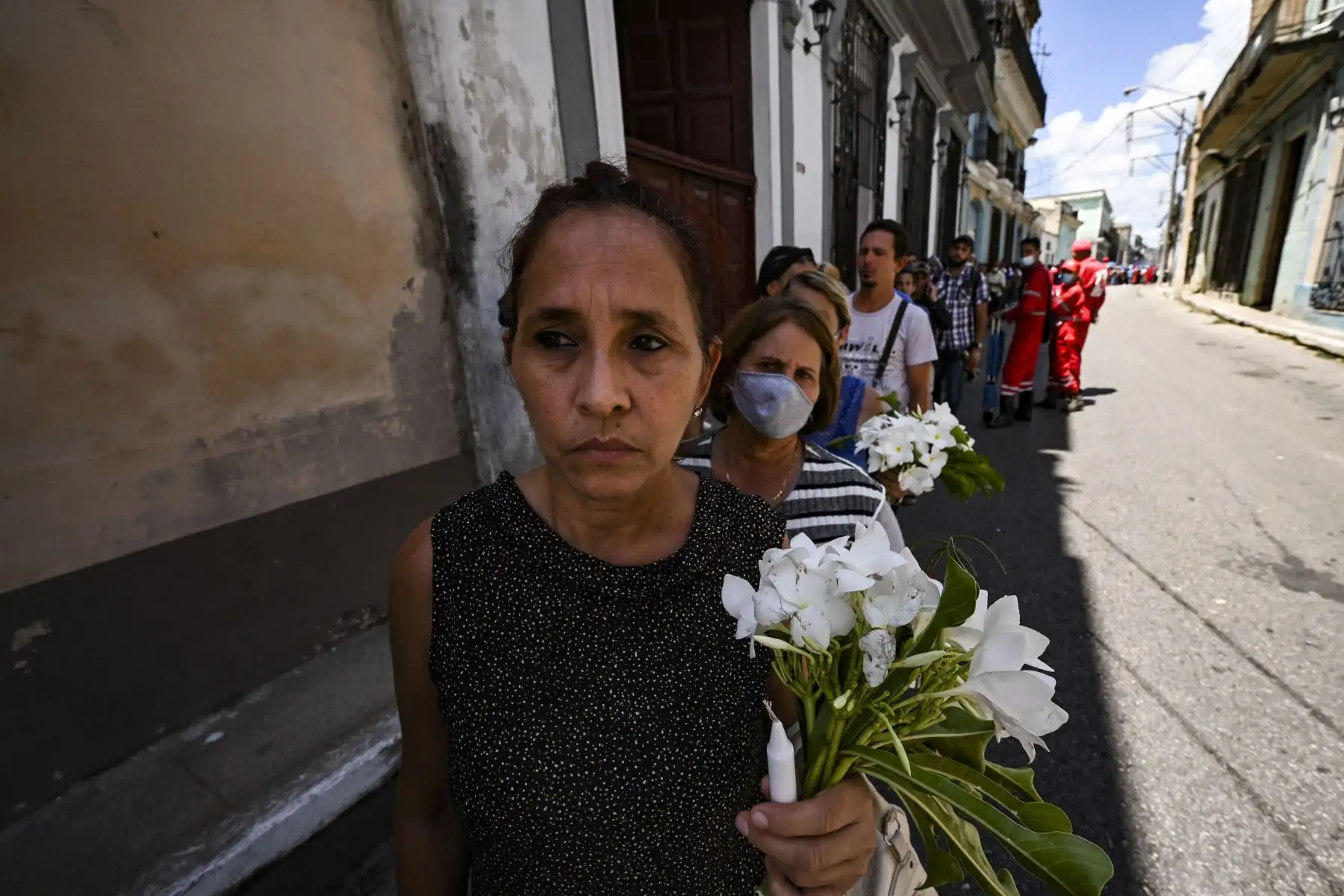 Personas con flores hacen fila para rendir homenaje a 14 bomberos que murieron en un gran incendio en un depósito de petróleo a principios de agosto, durante el funeral en el Museo de los Bomberos en Matanzas, Cuba.
Foto: AFP