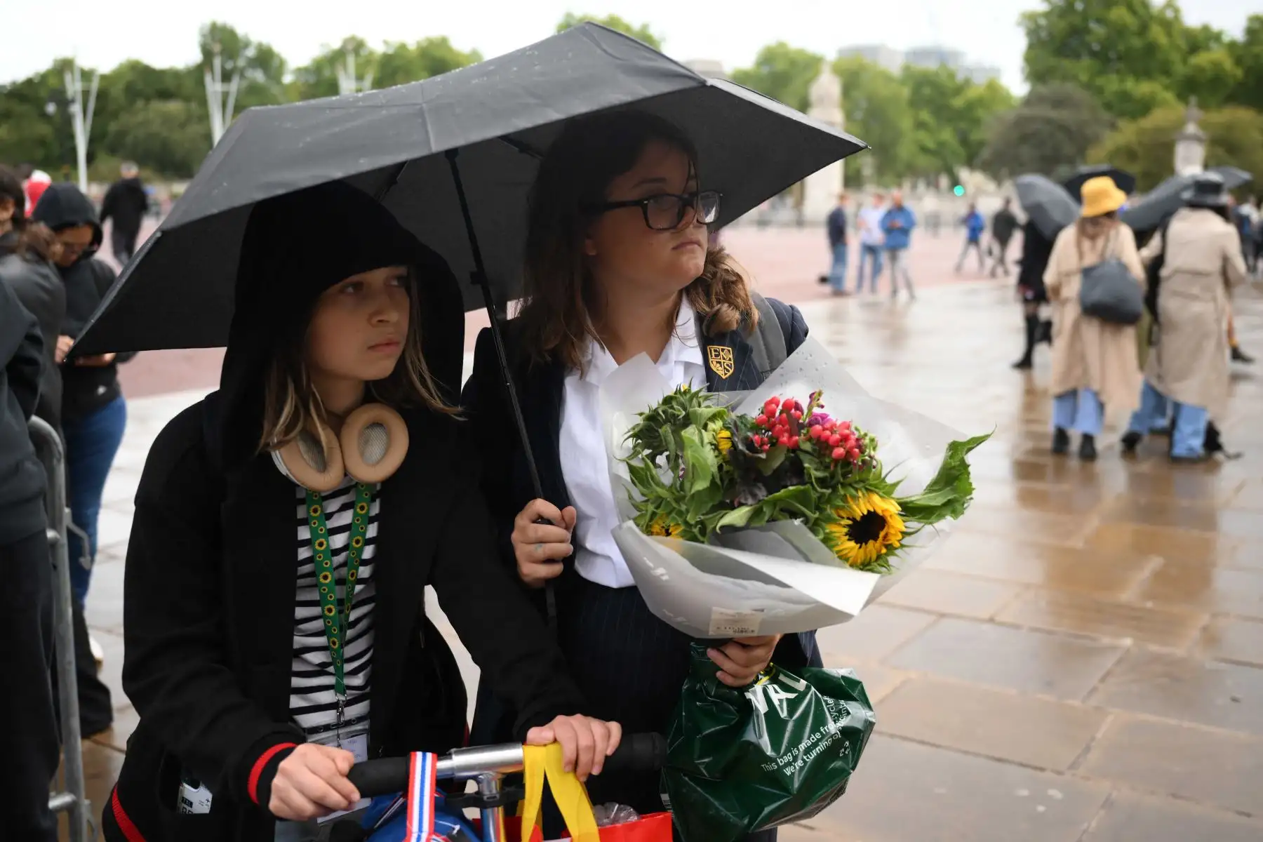 Los simpatizantes traen flores mientras llueve afuera del Palacio de Buckingham, en el centro de Londres. Foto: AFP