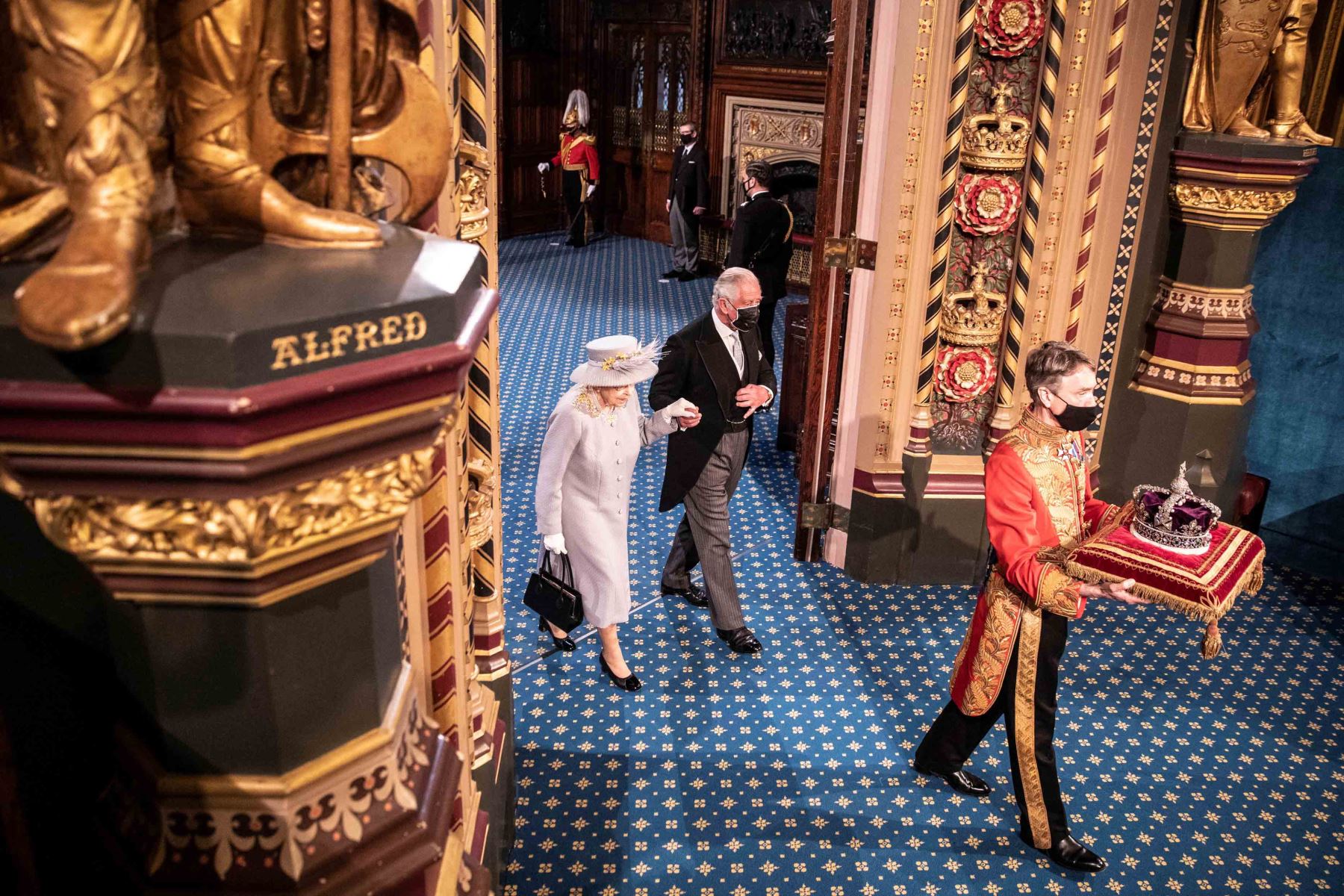 Foto de archivo tomada el 11 de mayo de 2021, la Reina Isabel II de Gran Bretaña y el Príncipe Carlos de Gales de Gran Bretaña caminan detrás de la Corona del Estado Imperial mientras recorren la Galería Real, después del discurso de la Reina. Foto: AFP