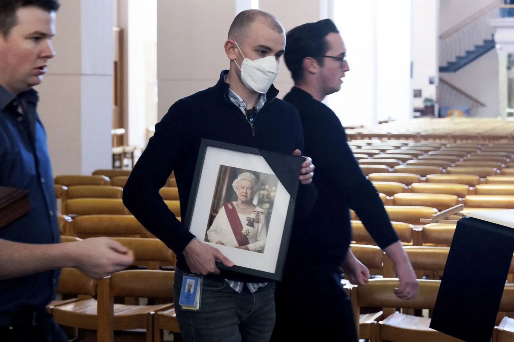 Un miembro del personal del departamento de Asuntos Internos lleva una foto de la reina Isabel a una mesa donde se instalará un libro de condolencias para que los miembros del público escriban en la Catedral de San Pablo de Wellington después de la muerte de la Reina en Wellington en septiembre. Foto: AFP