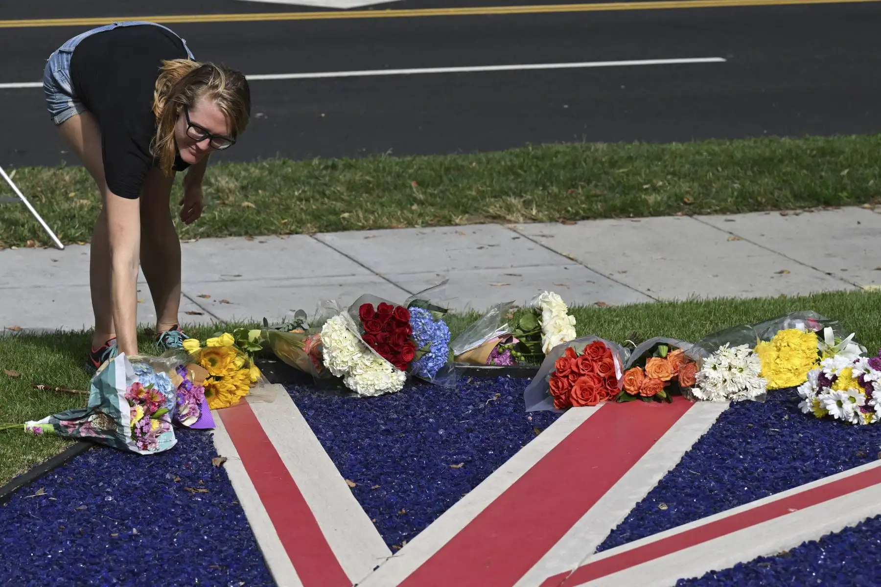 Una mujer coloca un ramo de flores en una bandera británica frente a la embajada británica en Washington, DC, el 8 de septiembre de 2022, tras la muerte de la reina Isabel II. Foto: AFP