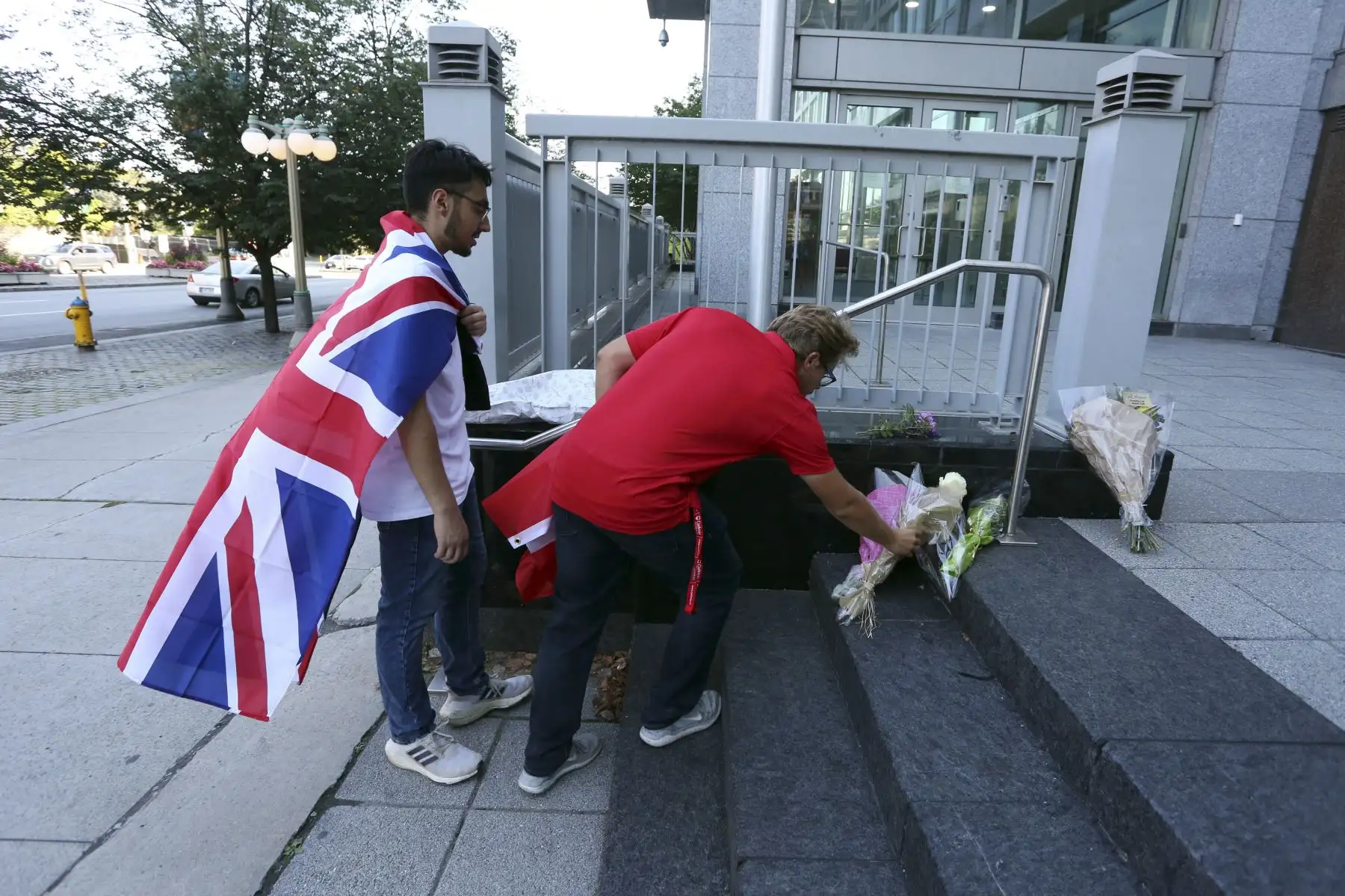 La doliente Eissa Saddozai (L) y Aidan Osadchuk colocan flores en los escalones de la Alta Comisión Británica después de la muerte de la Reina Isabel II de Gran Bretaña el 8 de septiembre de 2022 en Ottawa, Canadá. Foto: AFP