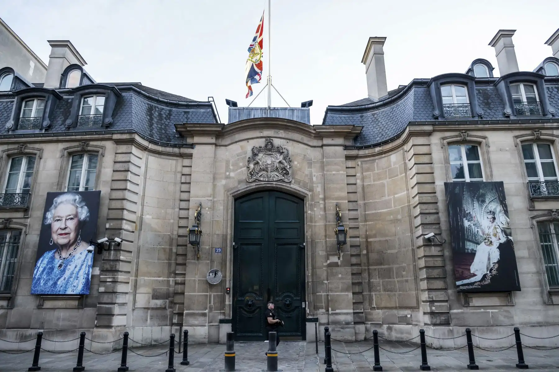 La Union Jack con el escudo de armas real ondea a media asta en la puerta principal de la embajada británica en París y dos retratos de la reina Isabel II cuelgan de sus paredes tras el anuncio de su muerte el 8 de septiembre de 2022. Foto: AFP