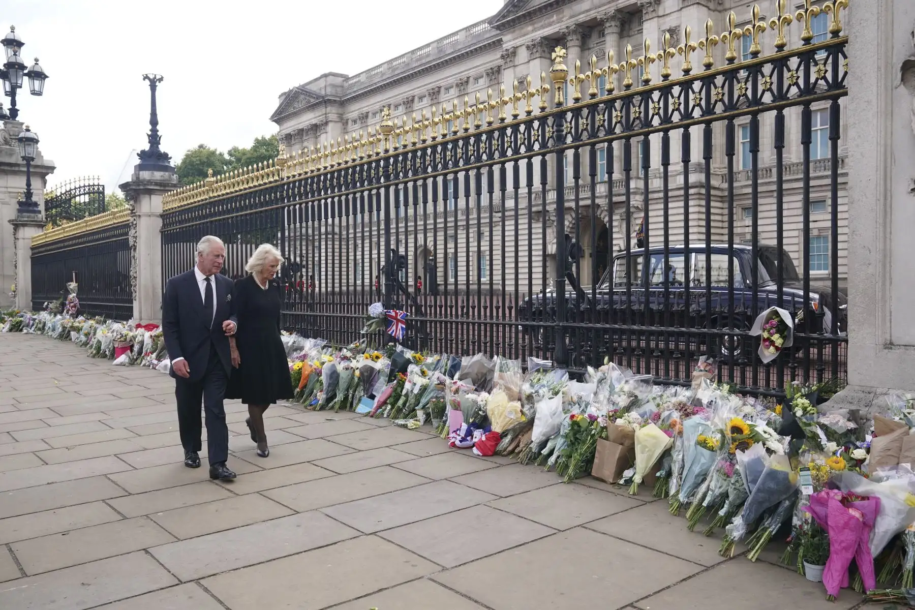 El rey Carlos III de Gran Bretaña y Camila, la reina consorte de Gran Bretaña, ven los tributos florales dejados fuera del Palacio de Buckingham en Londres, el 9 de septiembre de 2022, un día después de que la reina Isabel II muriera a la edad de 96 años. Foto: AFP