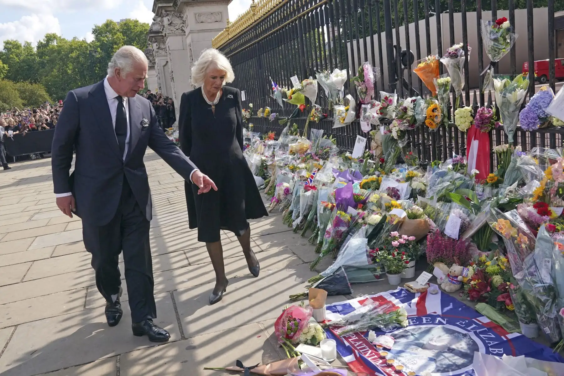El rey Carlos III de Gran Bretaña y Camila, la reina consorte de Gran Bretaña, ven los tributos florales dejados fuera del Palacio de Buckingham en Londres, el 9 de septiembre de 2022, un día después de que la reina Isabel II muriera a la edad de 96 años. Foto: AFP