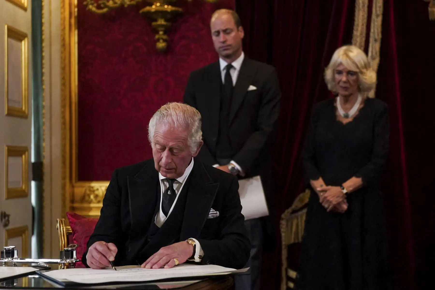 El Príncipe William, el Príncipe de Gales (C) de Gran Bretaña y la Reina Consorte (R) Camilla de Gran Bretaña observan cómo el Rey Carlos III de Gran Bretaña firma un juramento para defender la seguridad de la Iglesia en Escocia, durante una reunión del Consejo de Adhesión dentro del Palacio de St James en Londres el 10 de septiembre de 2022, para proclamarlo como nuevo Rey. Foto: AFP