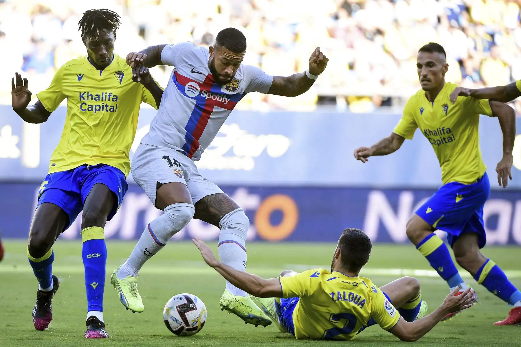 El delantero holandés del Barcelona Memphis Depay (C) lucha por el balón con el defensa senegalés de Cádiz Momo Mbaye (L) y el defensa español de Cádiz Joseba Zaldua (abajo) durante el partido de fútbol de la liga española entre el Cádiz CF y el FC Barcelona en el estadio Nuevo Mirandilla de Cádiz. Foto: AFP