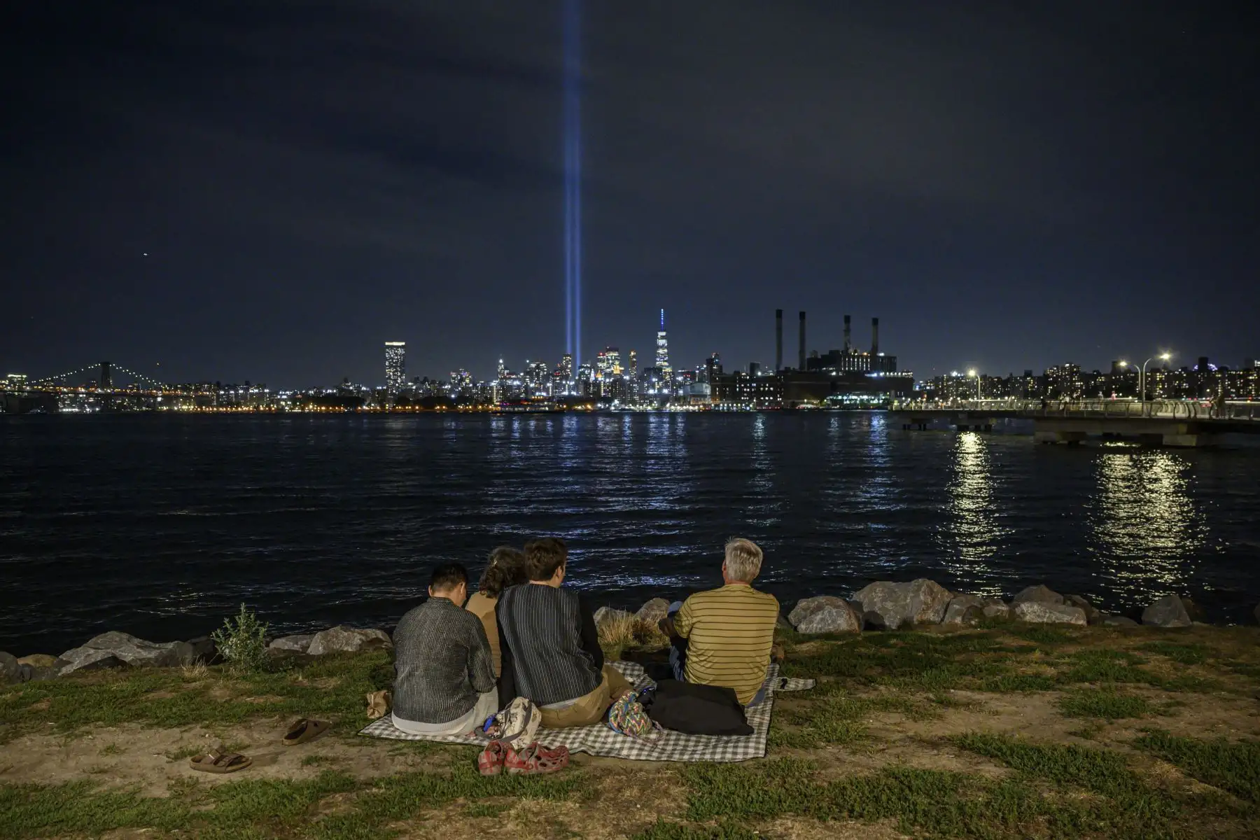 La gente se sienta frente al East River y la instalación 