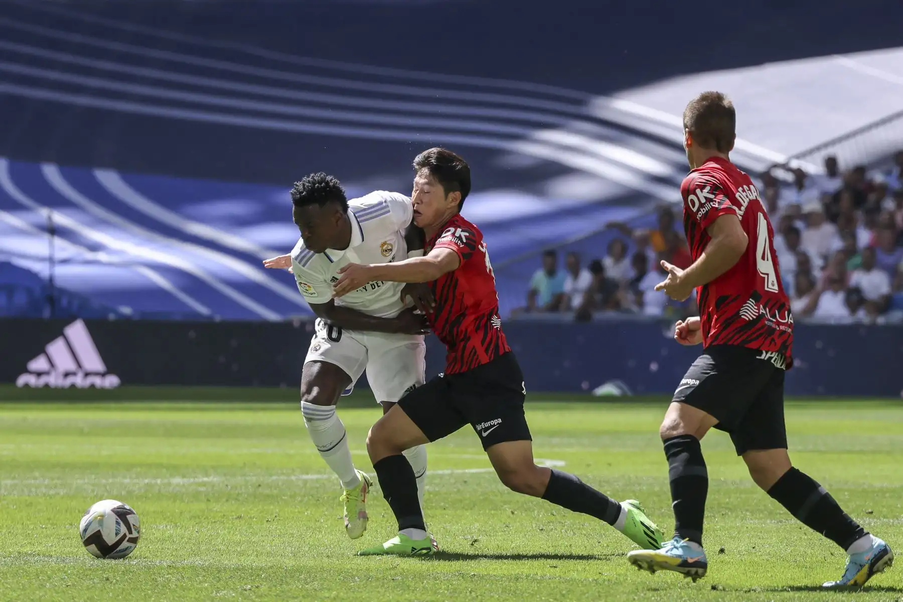 El delantero brasileño del Real Madrid Vinicius Junior (L) lucha por el balón con el delantero surcoreano del Real Mallorca Lee Kang-in (C) durante el partido de fútbol de la liga española entre el Real Madrid CF y el RCD Mallorca en el estadio Santiago Bernabeu en Madrid. Foto: AFP