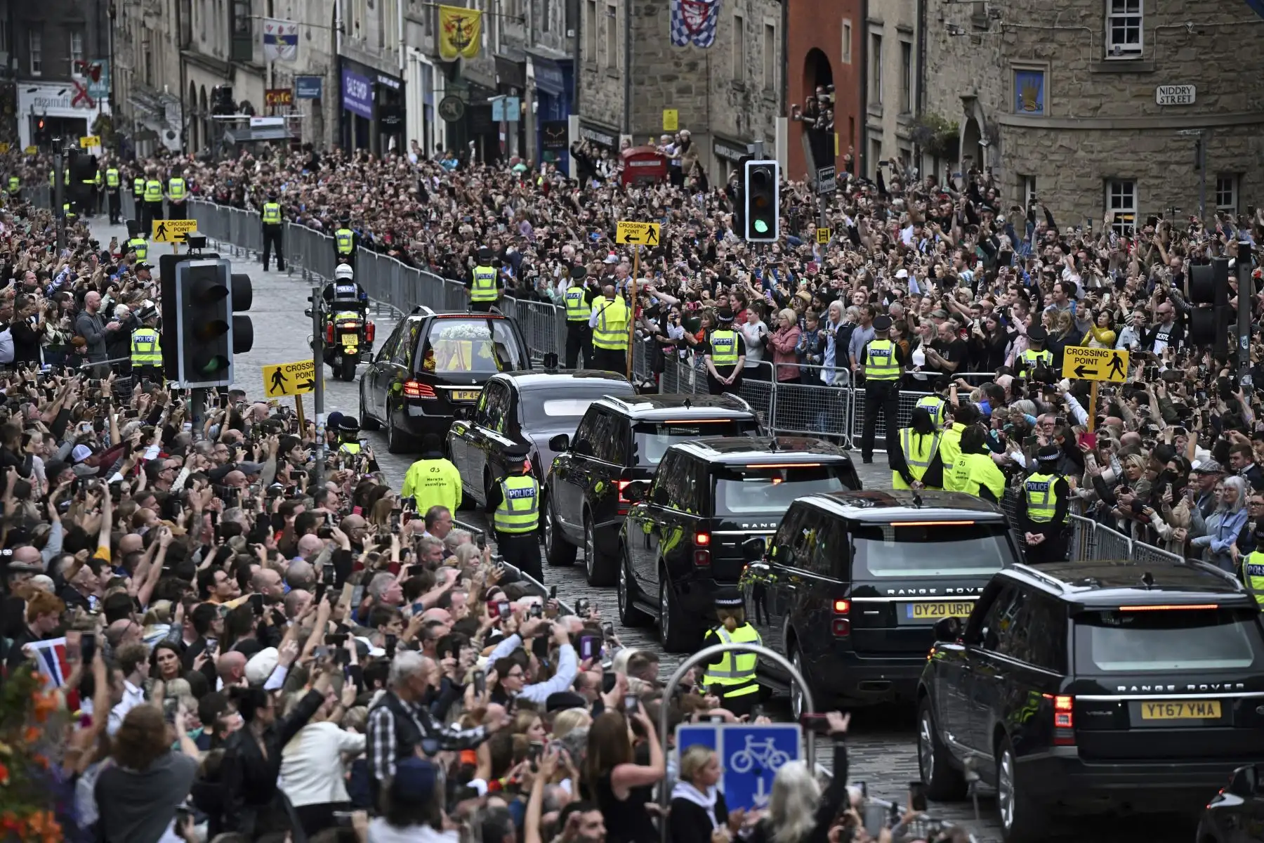 Los miembros del público observan el coche fúnebre que lleva el ataúd de la reina Isabel II, envuelto en el estandarte real de Escocia, mientras se conduce a través de Edimburgo hacia el Palacio de Holyroodhouse. Foto: AFP