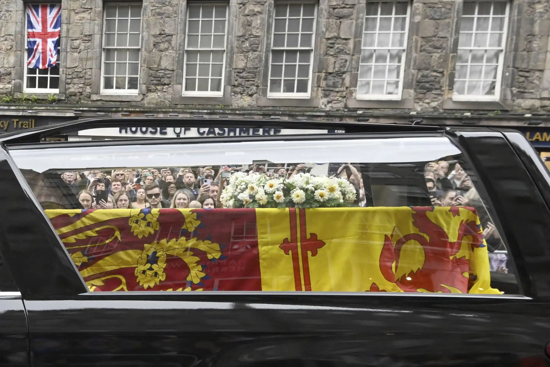 Los miembros del público observan el coche fúnebre que lleva el ataúd de la reina Isabel II, envuelto en el estandarte real de Escocia, mientras se conduce a través de Edimburgo hacia el Palacio de Holyroodhouse. Foto: AFP