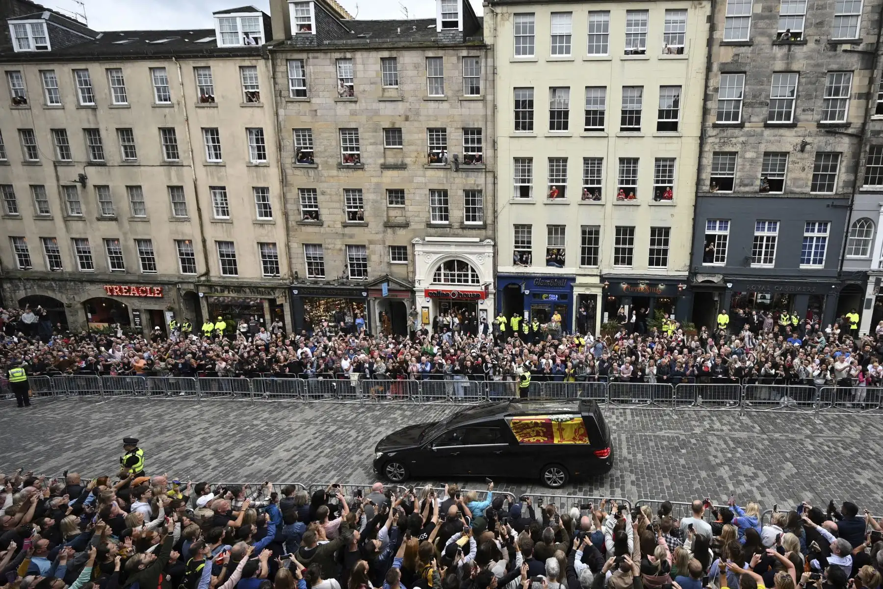Los miembros del público observan el coche fúnebre que lleva el ataúd de la reina Isabel II, envuelto en el estandarte real de Escocia, mientras se conduce a través de Edimburgo hacia el Palacio de Holyroodhouse. Foto: AFP