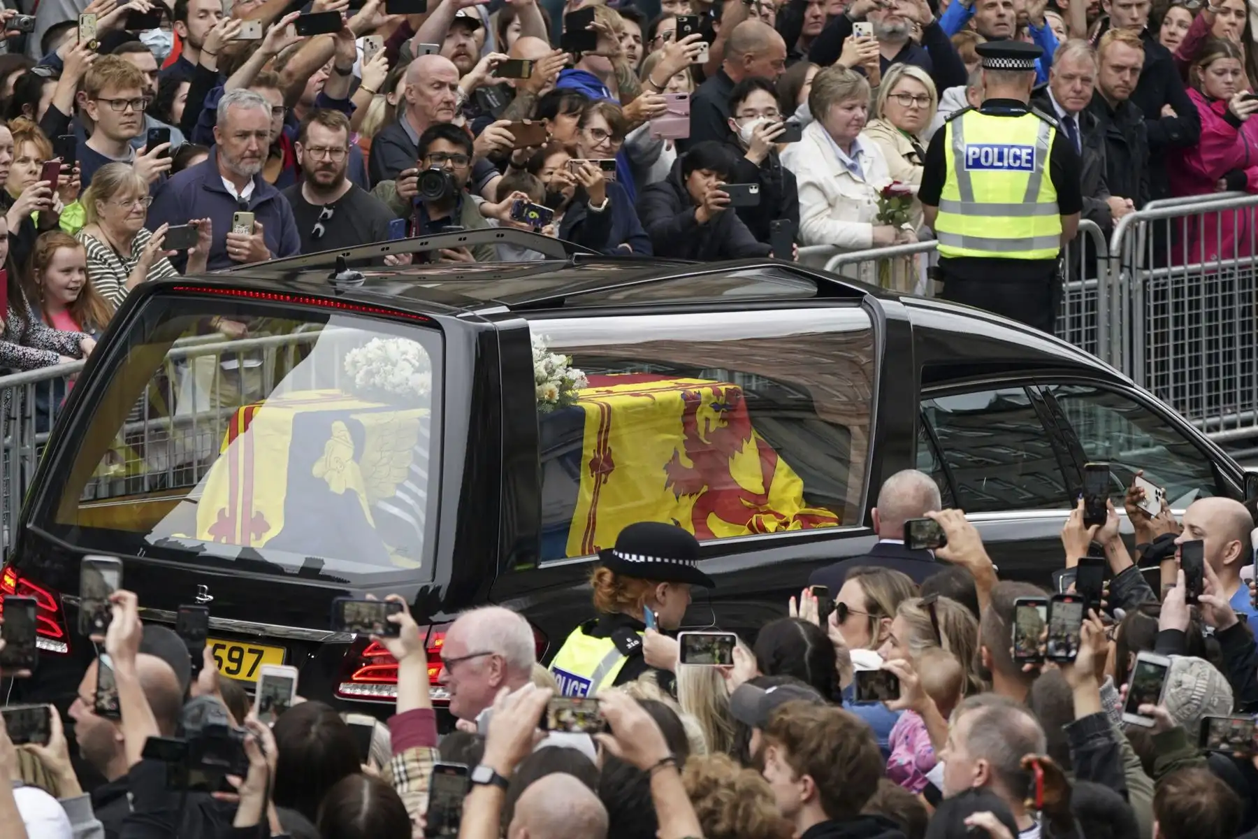 Los miembros del público observan el coche fúnebre que lleva el ataúd de la reina Isabel II, envuelto en el estandarte real de Escocia, mientras se conduce a través de Edimburgo hacia el Palacio de Holyroodhouse. Foto: AFP