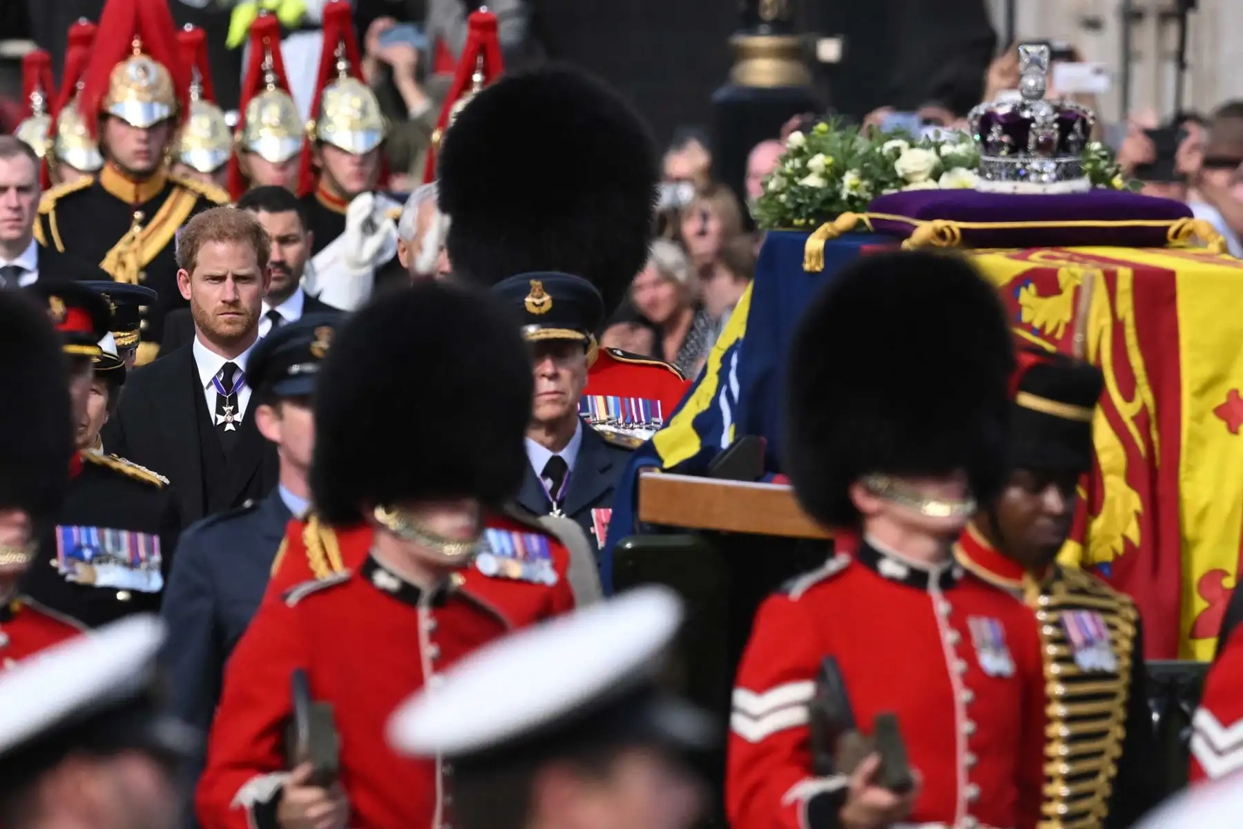 El príncipe Harry de Gran Bretaña, duque de Sussex, camina detrás del ataúd de la reina Isabel II, adornada con un estandarte real y la corona del estado imperial y tirada por un carruaje de artillería a caballo real de la tropa del rey, durante una procesión desde el Palacio de Buckingham hasta el Palacio de Westminster, en Londres. Foto: AFP