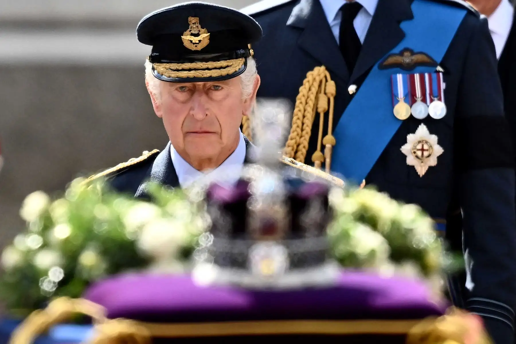 El rey Carlos III de Gran Bretaña camina detrás del ataúd de la reina Isabel II, adornada con un estandarte real y la corona del estado imperial y tirada por un carruaje de artillería a caballo real de la tropa del rey, durante una procesión desde el Palacio de Buckingham hasta el Palacio de Westminster, en Londres. Foto: AFP