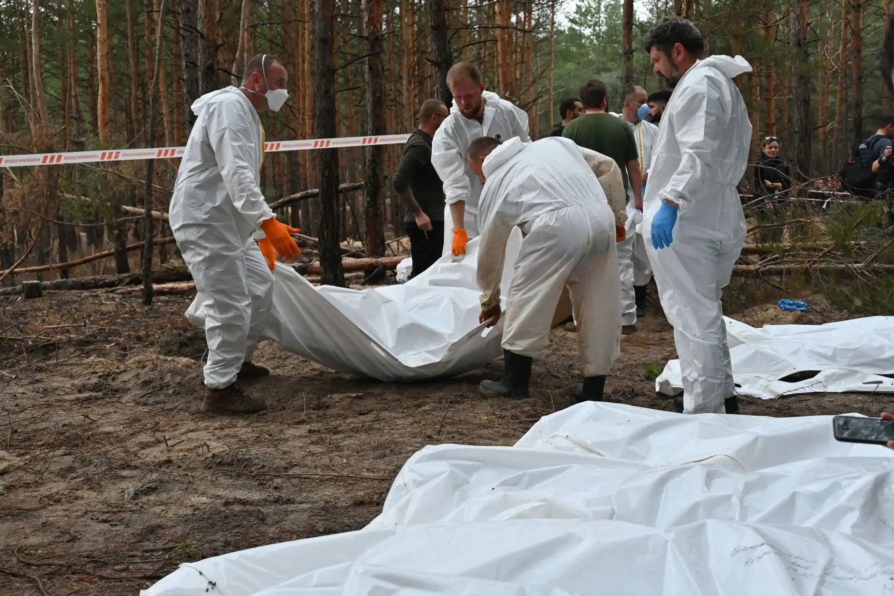 Técnicos forenses cavan una tumba en un bosque en las afueras de Izyum, este de Ucrania, el 16 de septiembre de 2022. - Ucrania dijo el 16 de septiembre de 2022 que había contado 450 tumbas en un solo lugar de entierro cerca de Izyum después de recuperar la ciudad del este de los rusos. Foto: AFP