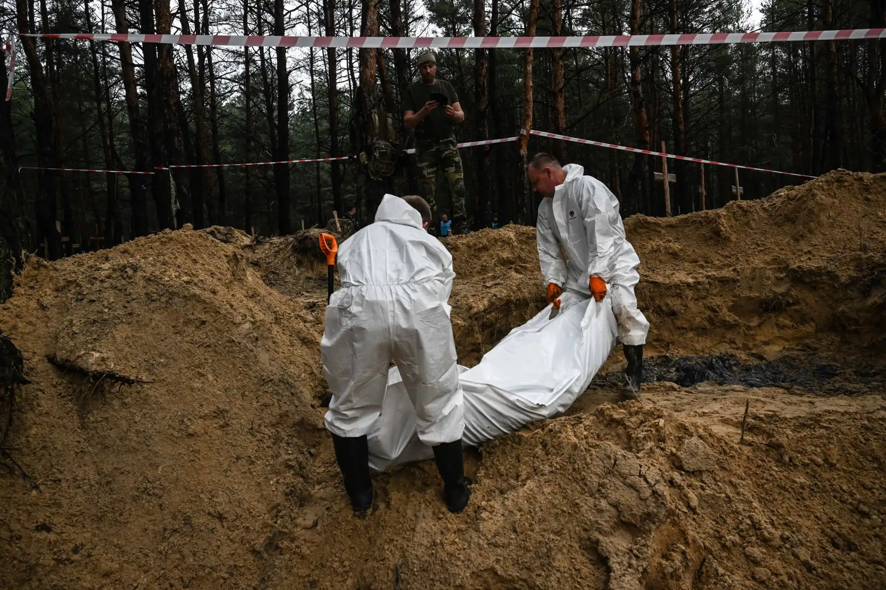 Técnicos forenses cavan una tumba en un bosque en las afueras de Izyum, este de Ucrania, el 16 de septiembre de 2022. - Ucrania dijo el 16 de septiembre de 2022 que había contado 450 tumbas en un solo lugar de entierro cerca de Izyum después de recuperar la ciudad del este de los rusos. Foto: AFP