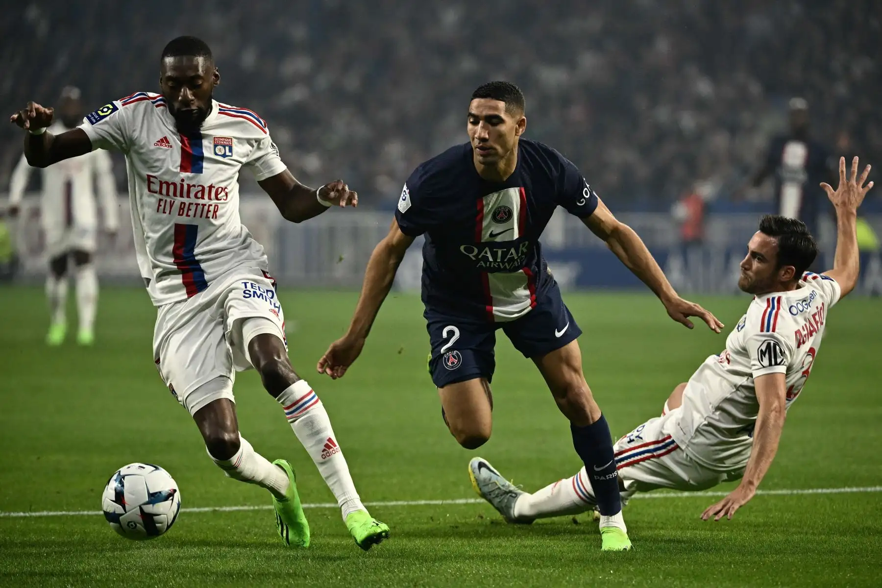 Achraf Hakimi (C), defensor marroquí del Paris Saint-Germain, y Karl Toko Ekambi (L), delantero camerunés del Lyon, luchan por el balón durante el partido de fútbol de la L1 francesa entre el Olympique Lyonnais (OL) y el Paris Saint-Germain (PSG) en el estadio Groupama de Decines-Charpieu, centro-este de Francia. Foto: AFP