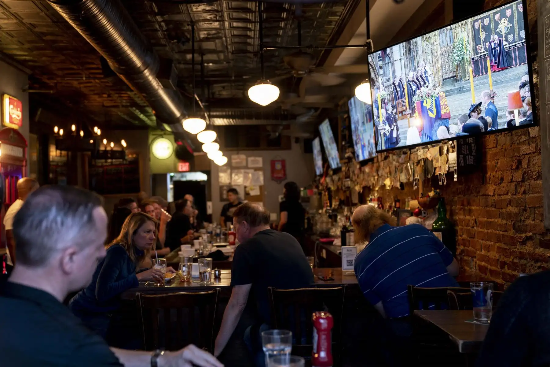 La gente ve el funeral de estado de la reina Isabel II en el pub The Queen Vic en Washington, DC. Foto: AFP