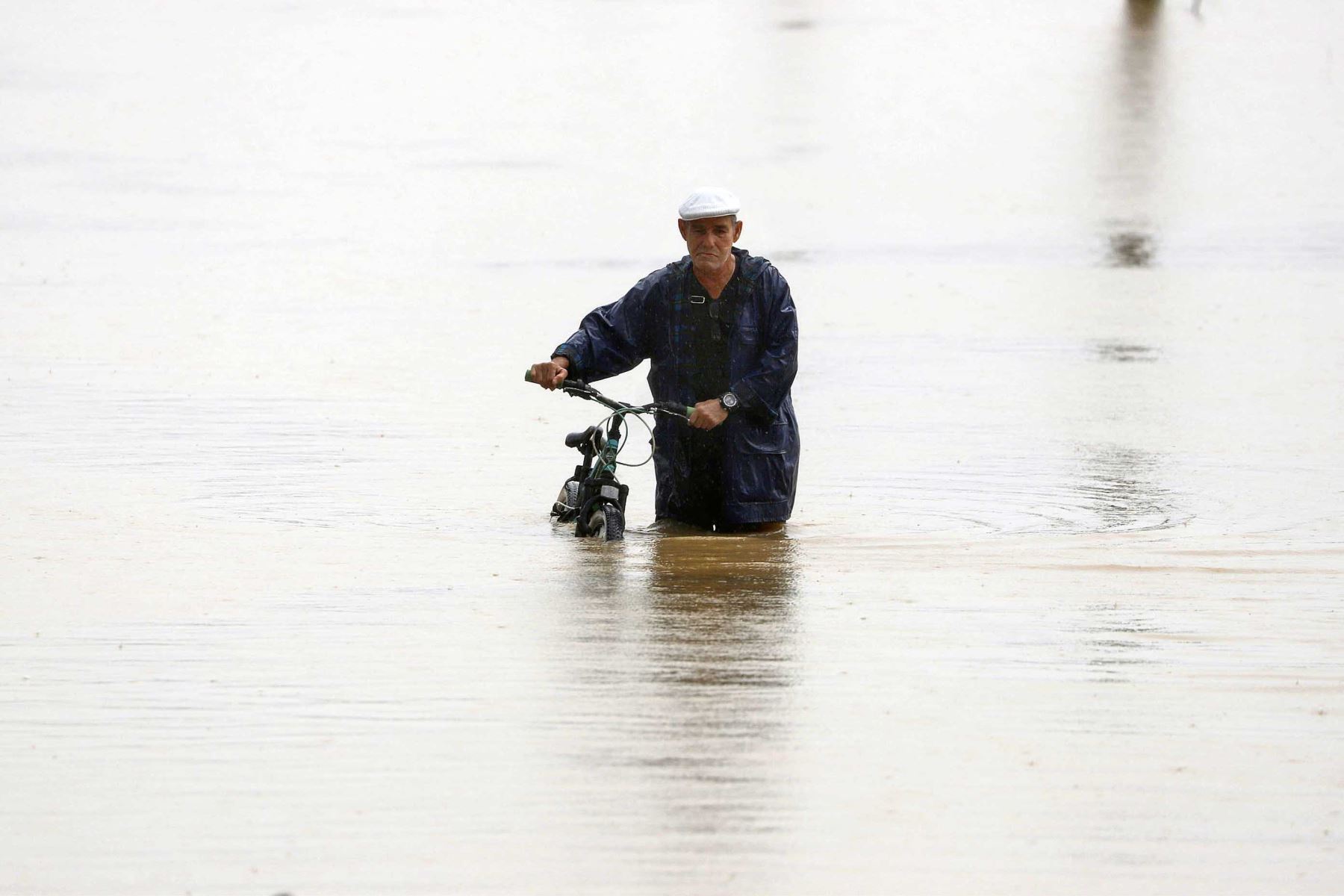 Un hombre cruza con su bicicleta una calle inundada debido a lluvias por el paso del huracán Fiona. Foto: EFE