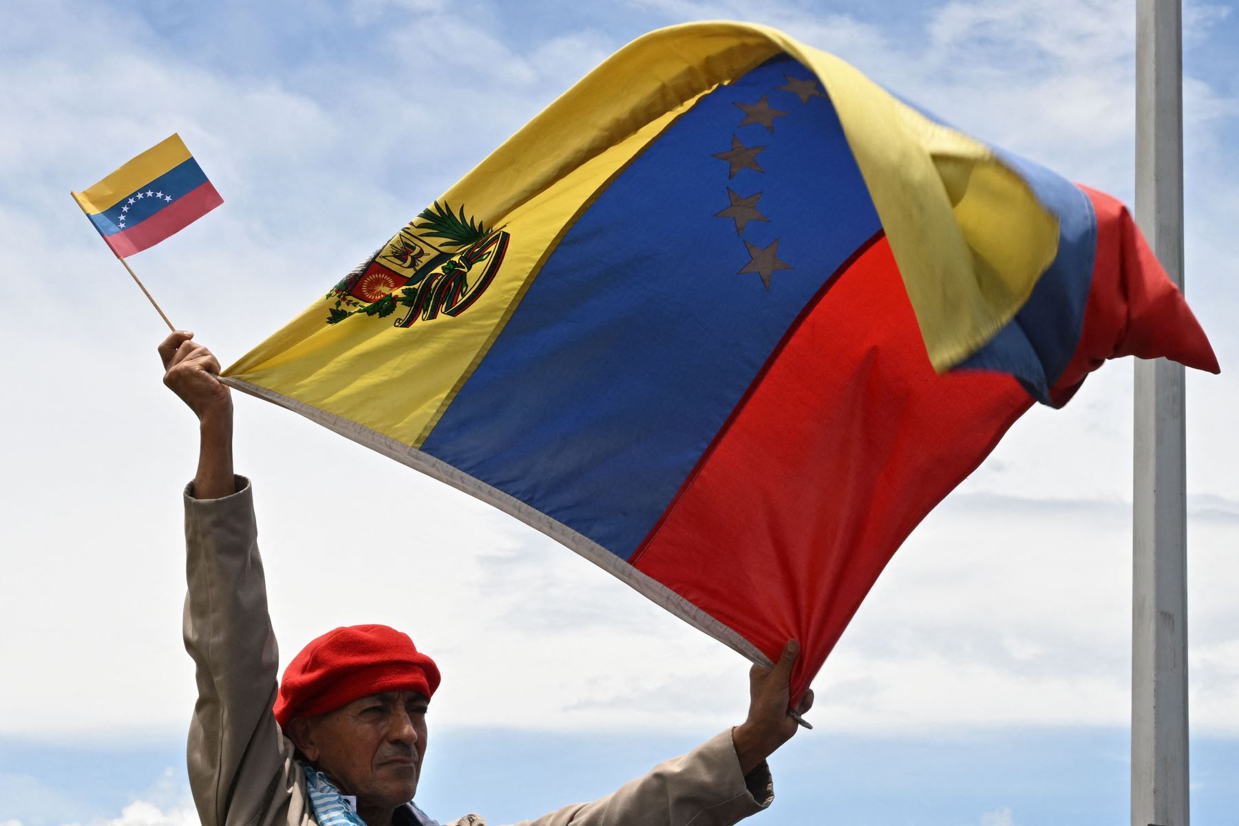 Un hombre ondea banderas venezolanas durante la ceremonia en la que se reabrió oficialmente la frontera terrestre entre Venezuela y Colombia después de estar completamente cerrada desde 2019, en el Puente Internacional Simón Bolívar.
Foto: AFP