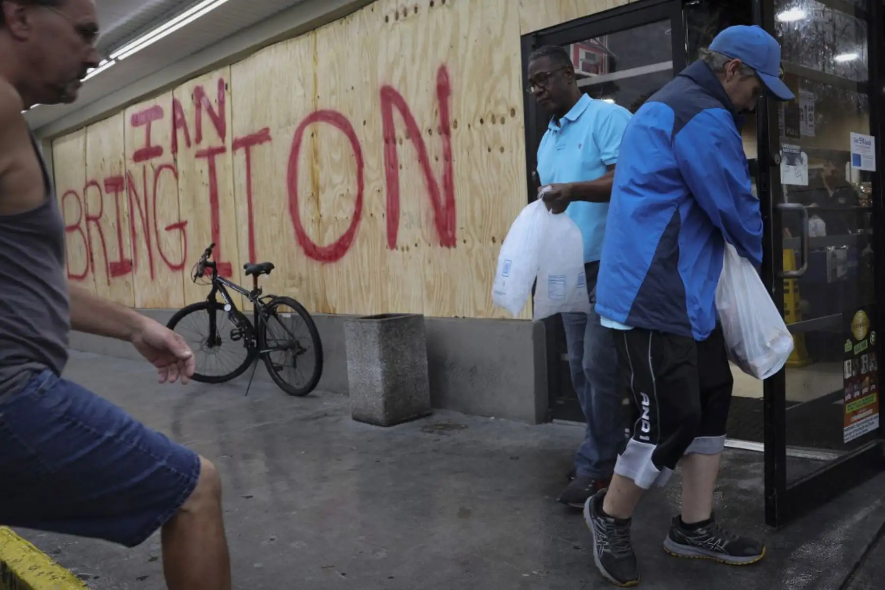 Clientes salen de una tienda tras recolectar suministros de última hora antes de la llegada del huracán Ian en Tampa, Florida. Foto: AFP