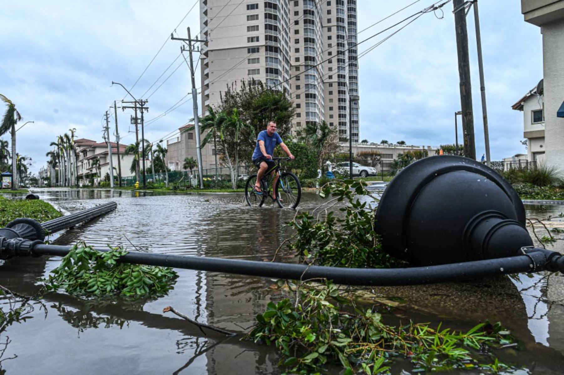 Un hombre monta en bicicleta a través del agua pasando una farola caída después del huracán Ian en Fort Myers, Florida. Foto: AFP