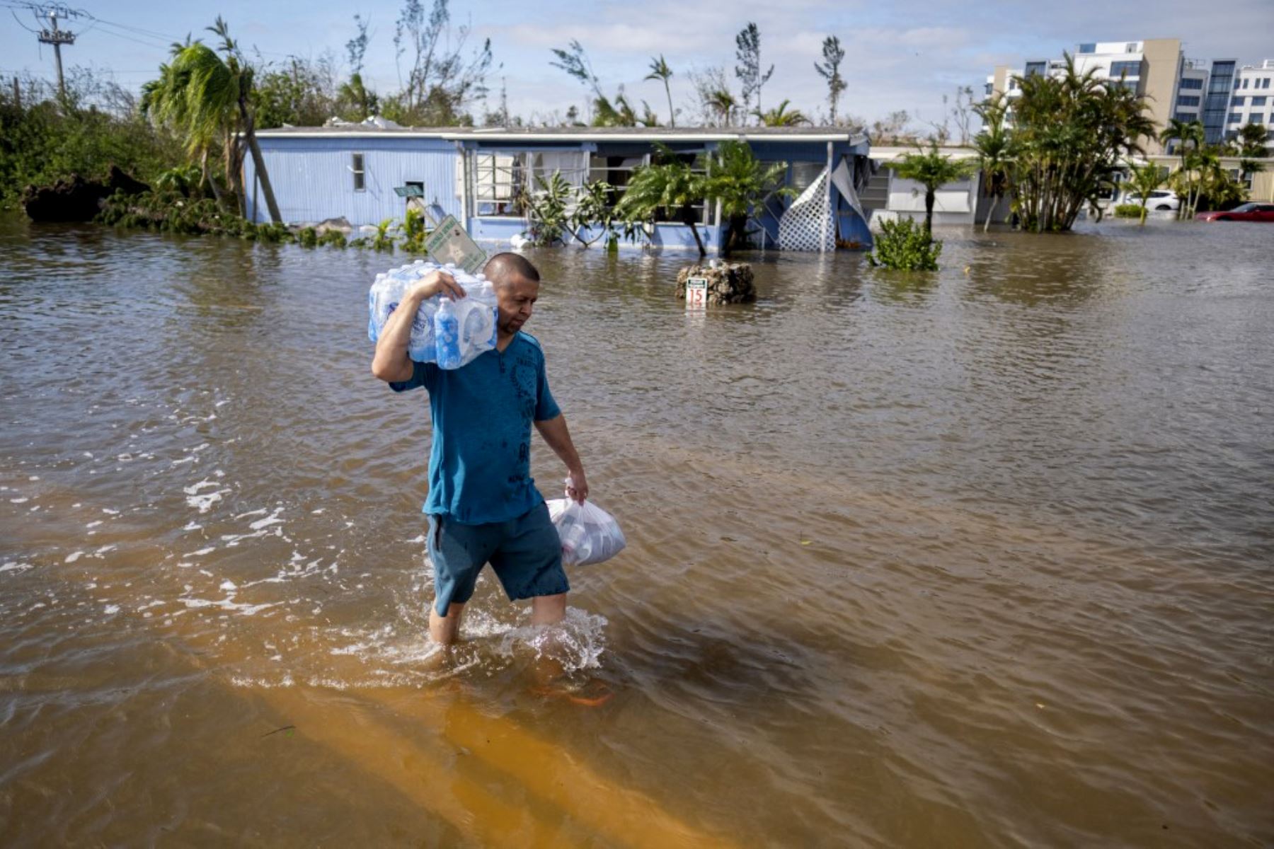 Un hombre que lleva agua embotellada camina por el agua en un vecindario inundado después del huracán Ian en Fort Myers, Florida. Foto: AFP