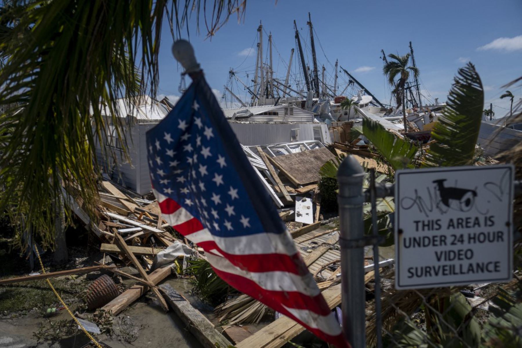 La bandera de EE. UU. ondea mientras se ve una pila de botes arrastrados por el agua en el fondo después del huracán Ian, en Fort Myers, Florida. Foto: AFP