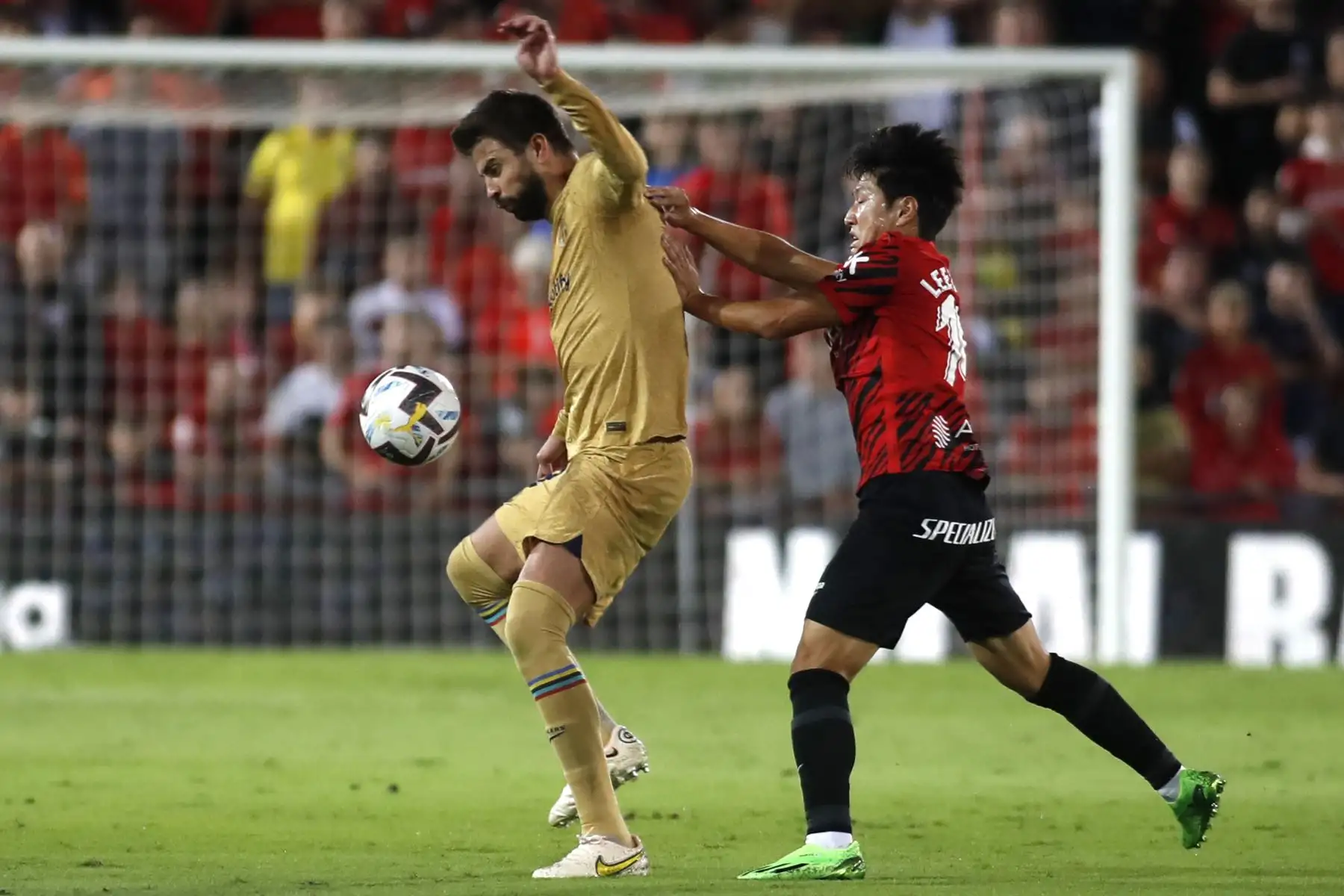 El defensor español de Barcelona, ​​Gerard Piqué, compite con el delantero surcoreano de Mallorca, Lee Kang-in, durante el partido de la Liga. Foto: AFP