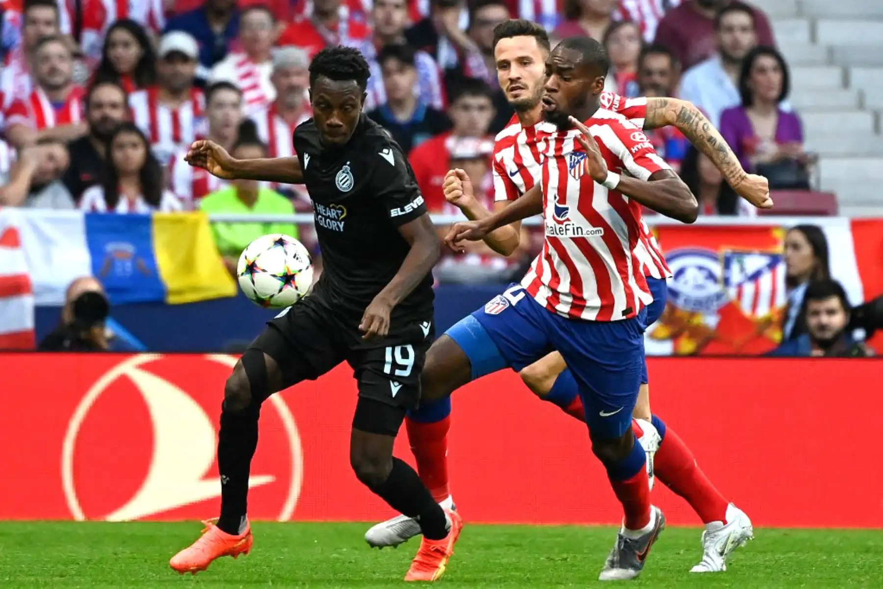 El delantero ghanés del Club Brugge, Kamal Sowah, es desafiado por el centrocampista español del Atlético de Madrid, Saul Niguez, y el centrocampista francés del Atlético de Madrid, Geoffrey Kondogbia, durante la primera ronda de la Liga de Campeones de la UEFA, grupo B, partido de fútbol entre el Club Atlético de Madrid y el Club Brugge en el estadio Wanda Metropolitano de Madrid. Foto: AFP