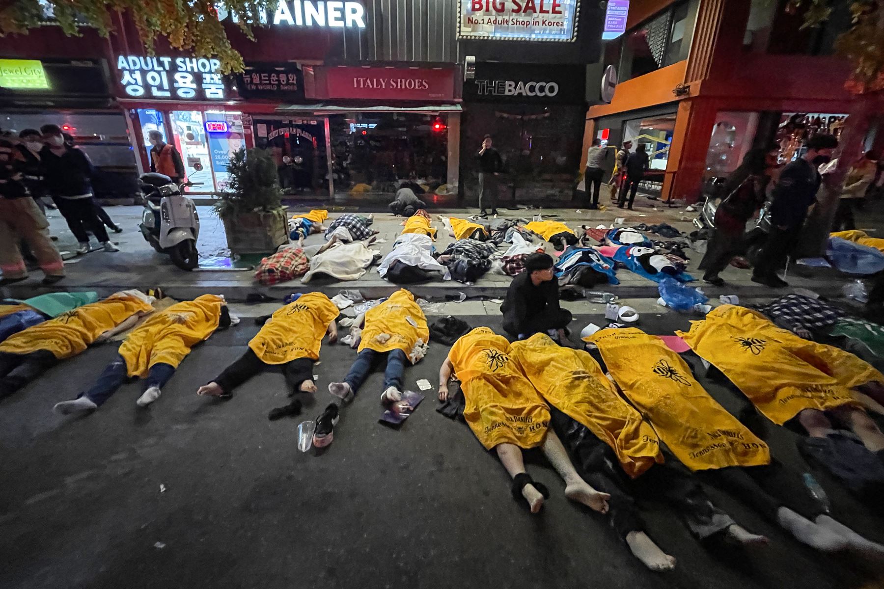 Los cuerpos de las víctimas que sufrieron un paro cardíaco durante una estampida, en medio de las celebraciones de Halloween, lucen cubiertos en plena calle del distrito de vida nocturna de Itaewon, en Seúl, Corea del Sur. Foto: AFP