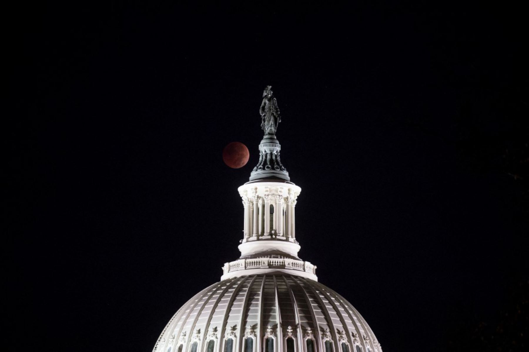 La Luna se pone durante un eclipse lunar total detrás de la Estatua de la Libertad en la parte superior de la cúpula del Capitolio de EE. UU. Foto: AFP