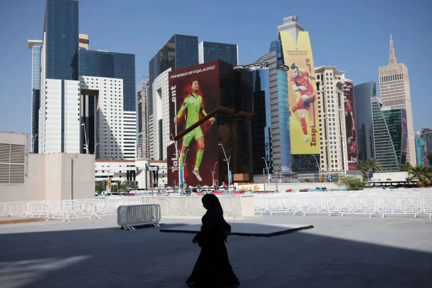 Los peatones caminan hacia la estación de metro frente a los edificios adornados con imágenes gigantes de futbolistas en West Bay en Doha, antes del torneo de fútbol de la Copa Mundial. Foto: AFP