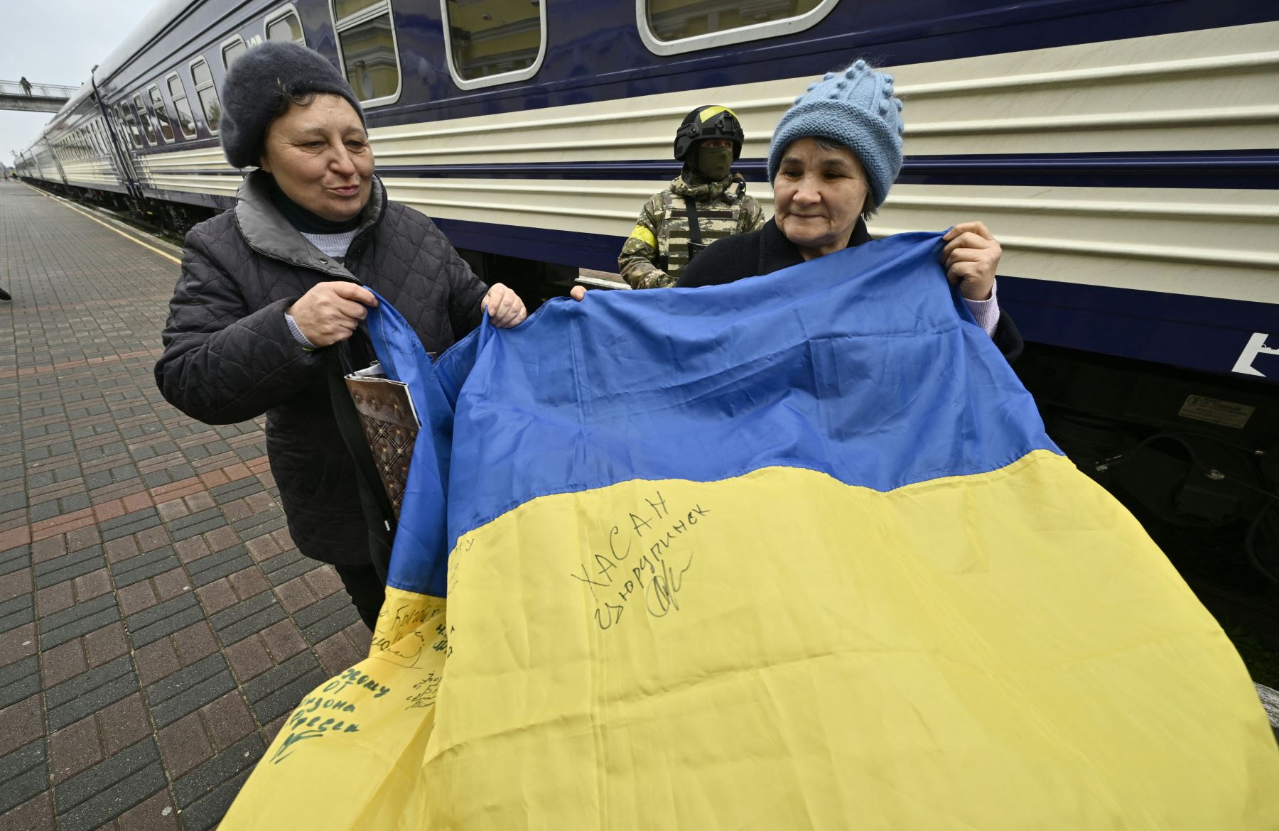 Los residentes locales sostienen una bandera ucraniana en la plataforma de la estación junto al primer tren de Kyiv a Kherson desde la invasión rusa de Ucrania, que llegó a la estación de tren de Kherson el 19 de noviembre de 2022. Foto: AFP