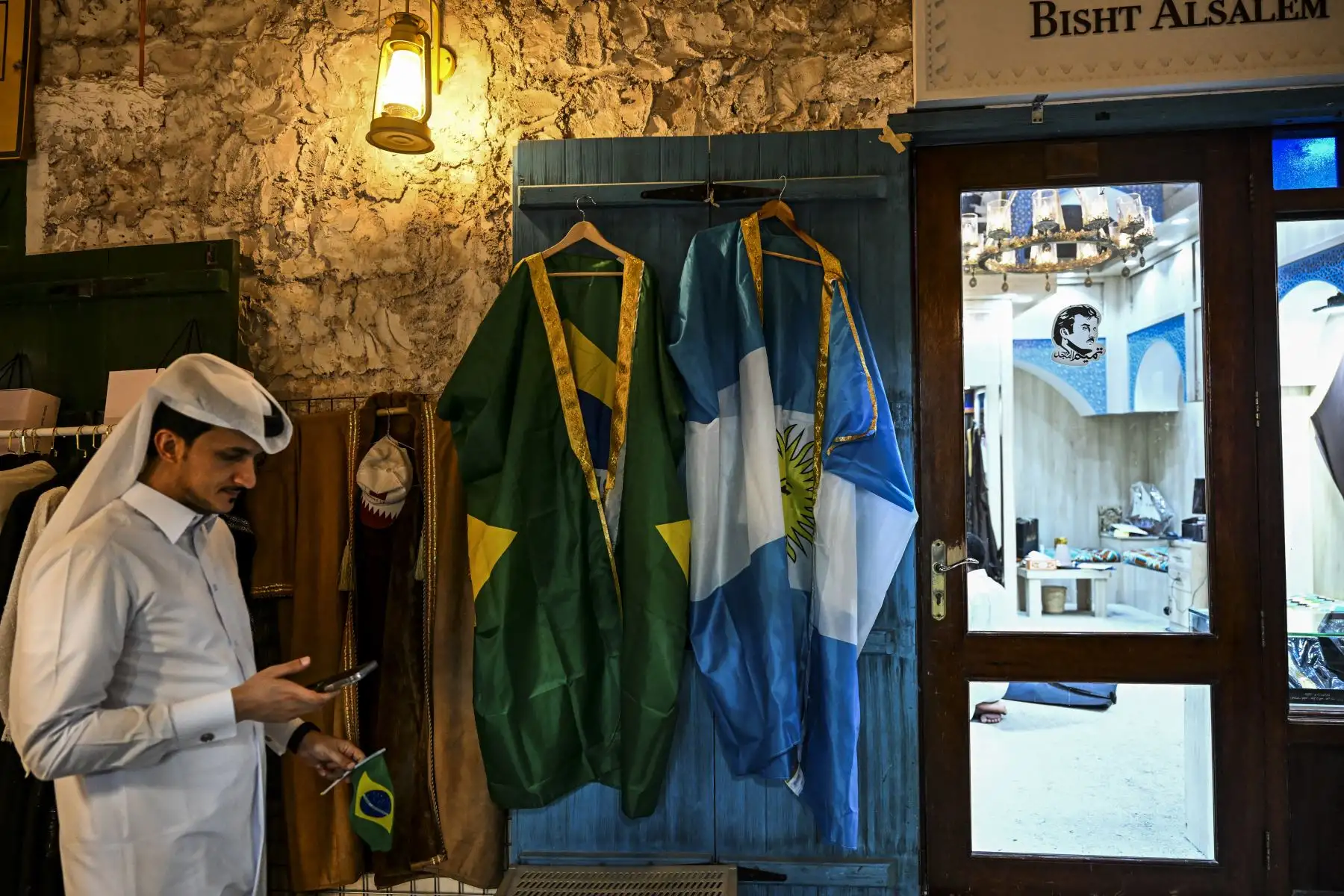 Un hombre pasa frente a una tienda que vende batas hechas con banderas brasileñas y argentinas en el mercado de Souq Waqif en Doha, antes del torneo de fútbol de la Copa Mundial de Qatar 2022

Foto: AFP