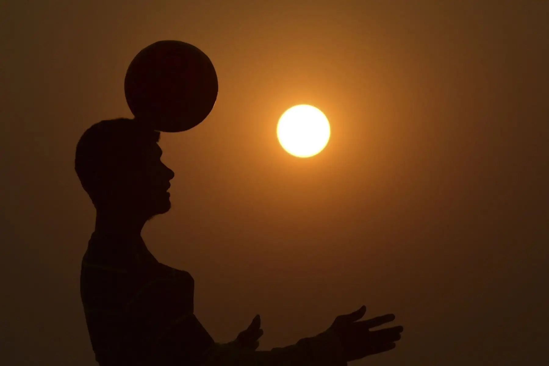 Un niño juega fútbol en un campo, antes del torneo de fútbol de la Copa Mundial de la FIFA Qatar 2022, en Prayagraj

Foto: AFP