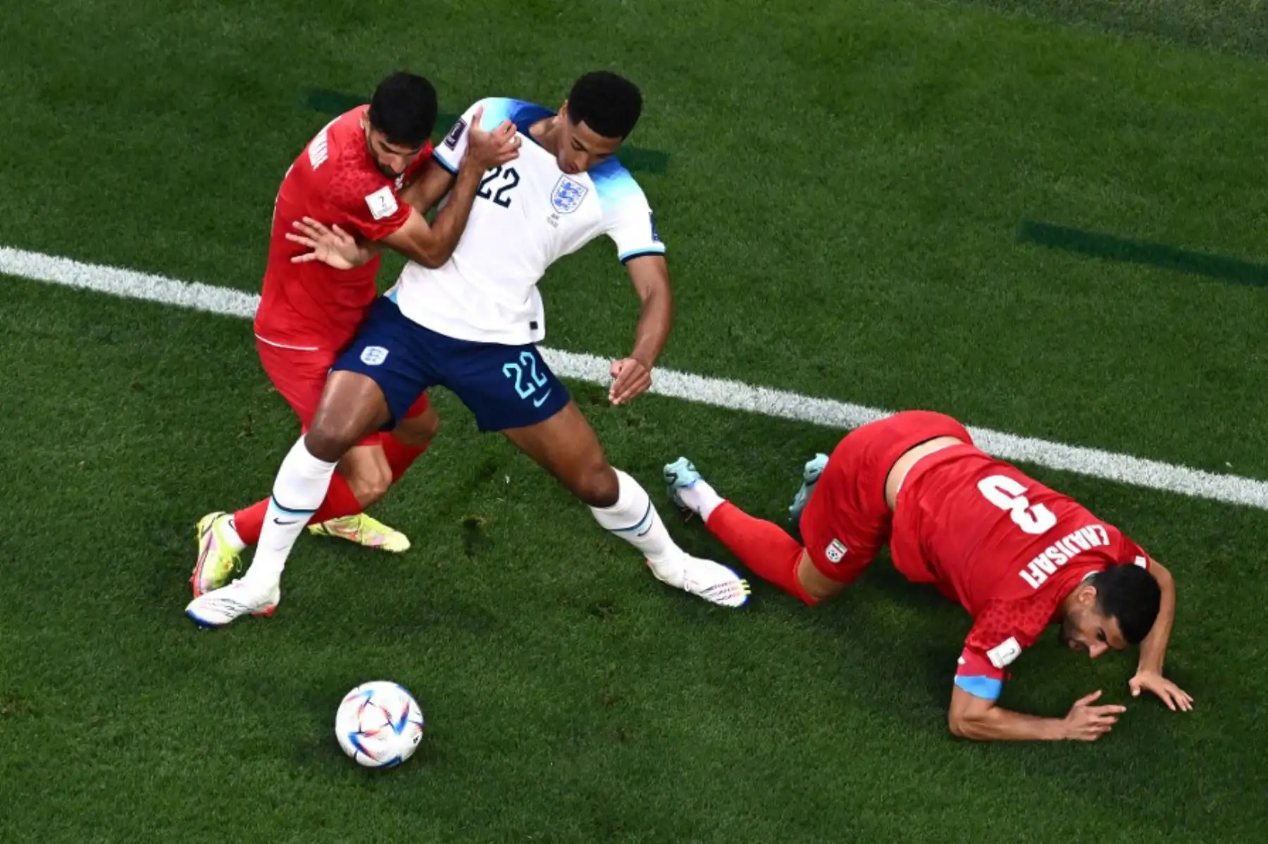 El mediocampista de Inglaterra Jude Bellingham, lucha por el balón con el defensor de Irán Ehsan Hajsafi  durante el partido de fútbol del Grupo B de la Copa Mundial de Catar 2022 entre Inglaterra e Irán en el Estadio Internacional Khalifa en Doha. Foto: AFP