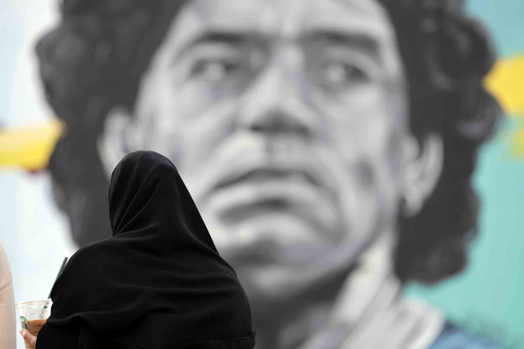 Una mujer catarí observa un mural del exjugador argentino Diego Armando Maradona, enfrente del estadio Al Khalifa de Doha, Catar. Foto: EFE