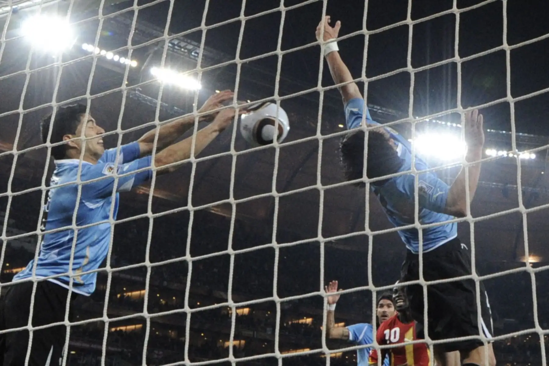 En esta foto de archivo tomada el 2 de julio de 2010, el delantero uruguayo Luis Suárez (izq.) detiene el balón con la mano, lo que provoca una tarjeta roja y un penalti para Ghana durante la prórroga del partido de cuartos de final de la Copa del Mundo de 2010 entre Uruguay y Ghana.
Foto: AFP
