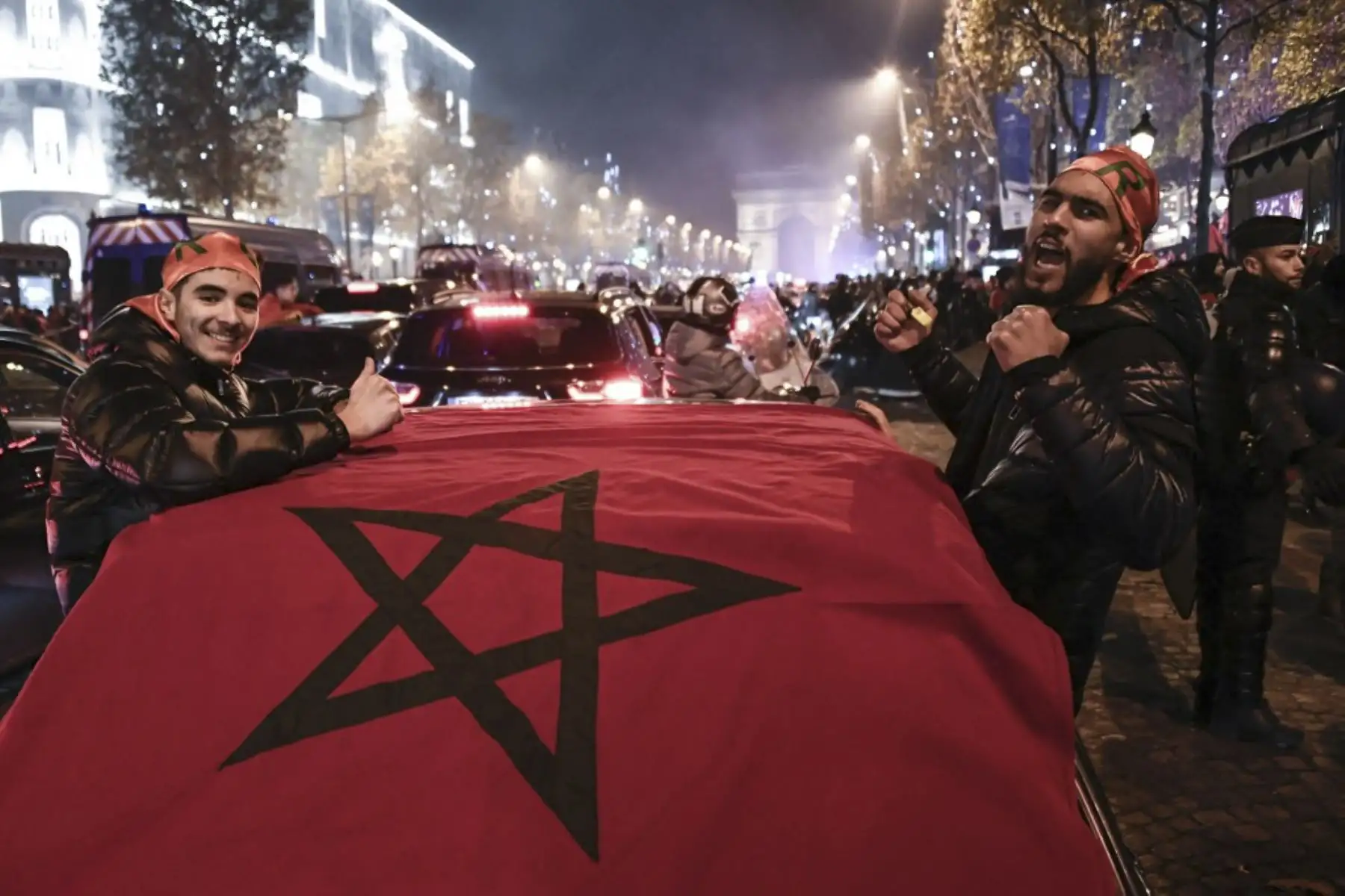 Los partidarios de Marruecos animan junto a una bandera nacional que cubre un automóvil mientras celebran la victoria de su equipo nacional después del partido de fútbol de la Copa Mundial de Catar 2022 entre Marruecos y España, en los Campos Elíseos

Foto:AFP