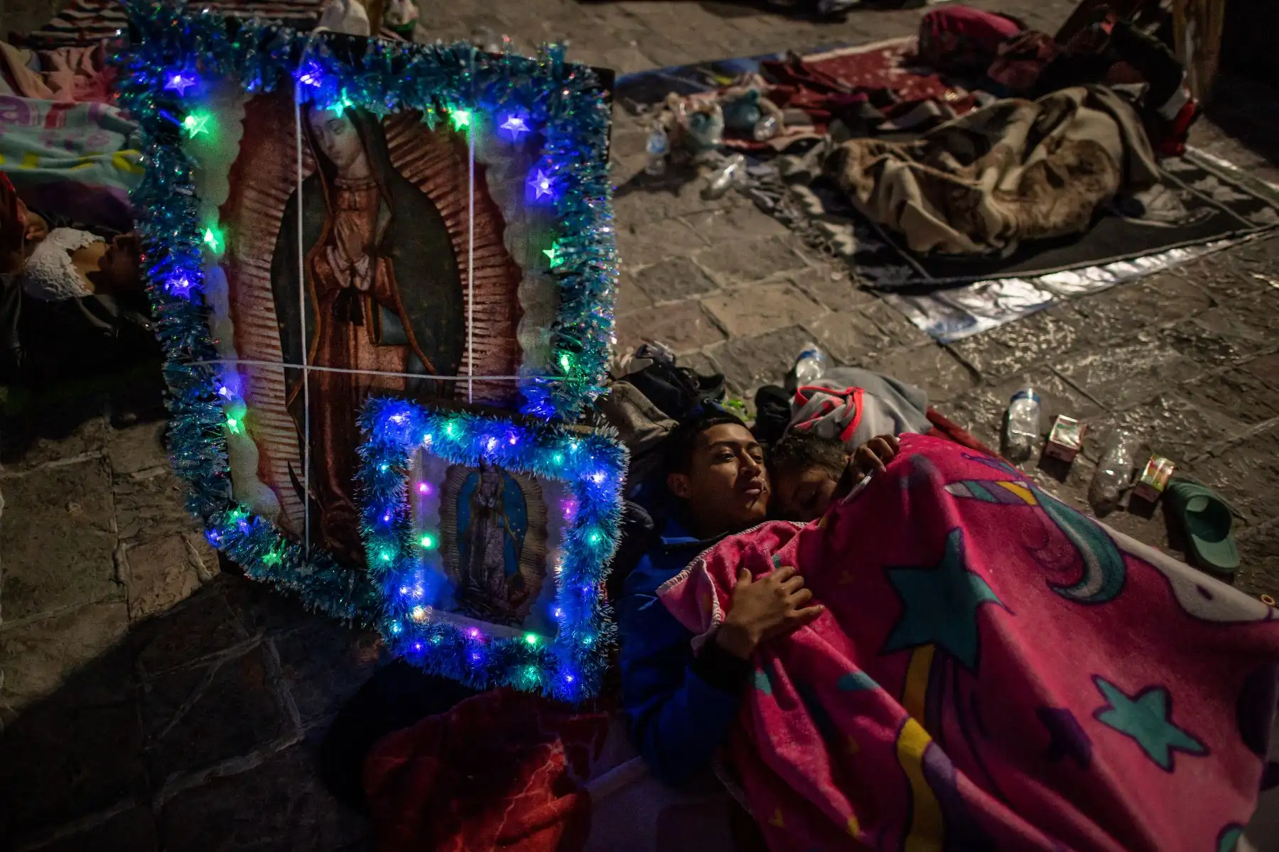 Una pareja descansa junto a las imágenes de la Virgen de Guadalupe en un campamento con otros peregrinos frente a la Basílica de Guadalupe en la Ciudad de México el 11 de diciembre de 2022.
Foto: AFP