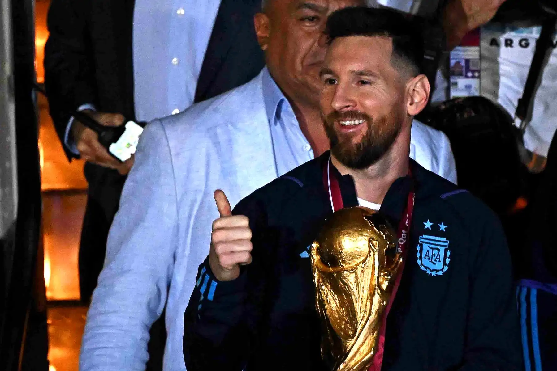 El capitán y delantero argentino Lionel Messi sostiene el Trofeo de la Copa Mundial de la FIFA junto con el entrenador argentino Lionel Scaloni  a su llegada al Aeropuerto Internacional de Ezeiza después de ganar el torneo de la Copa Mundial Qatar 2022 en Ezeiza, provincia de Buenos Aires, Argentina el 20 de diciembre de 2022. Foto: AFP